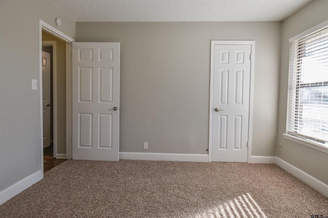 unfurnished bedroom with multiple windows, carpet floors, and a textured ceiling