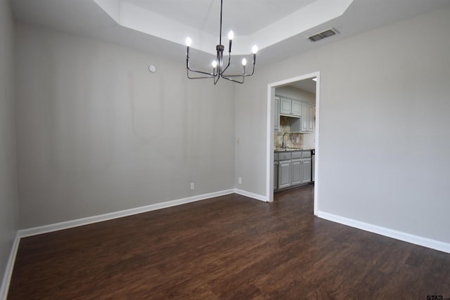 unfurnished dining area featuring a sink, visible vents, baseboards, dark wood-style floors, and a raised ceiling