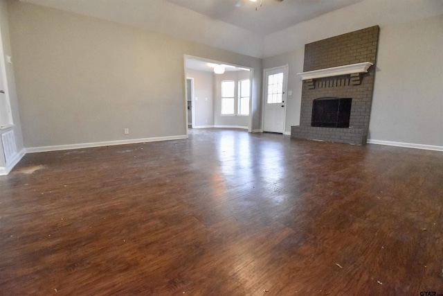 unfurnished living room featuring ceiling fan, dark hardwood / wood-style floors, a fireplace, and vaulted ceiling