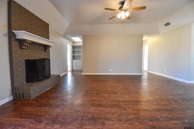 unfurnished living room with lofted ceiling, dark wood-type flooring, ceiling fan, built in shelves, and a fireplace