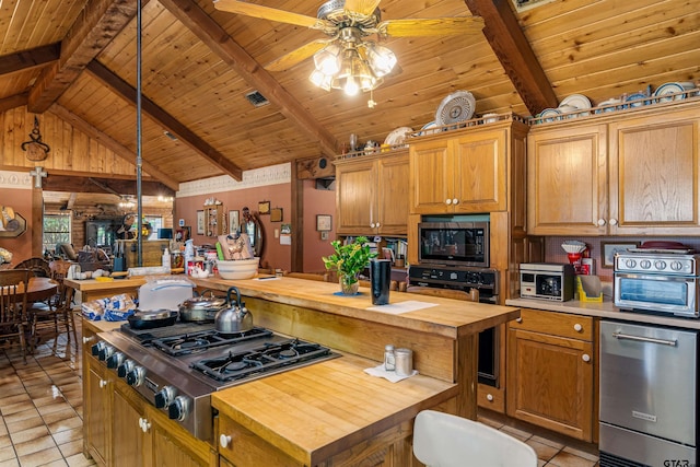 kitchen with butcher block countertops, decorative light fixtures, stainless steel appliances, and a kitchen island