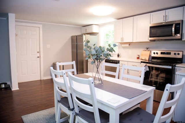 kitchen with stainless steel appliances, white cabinetry, and dark hardwood / wood-style flooring