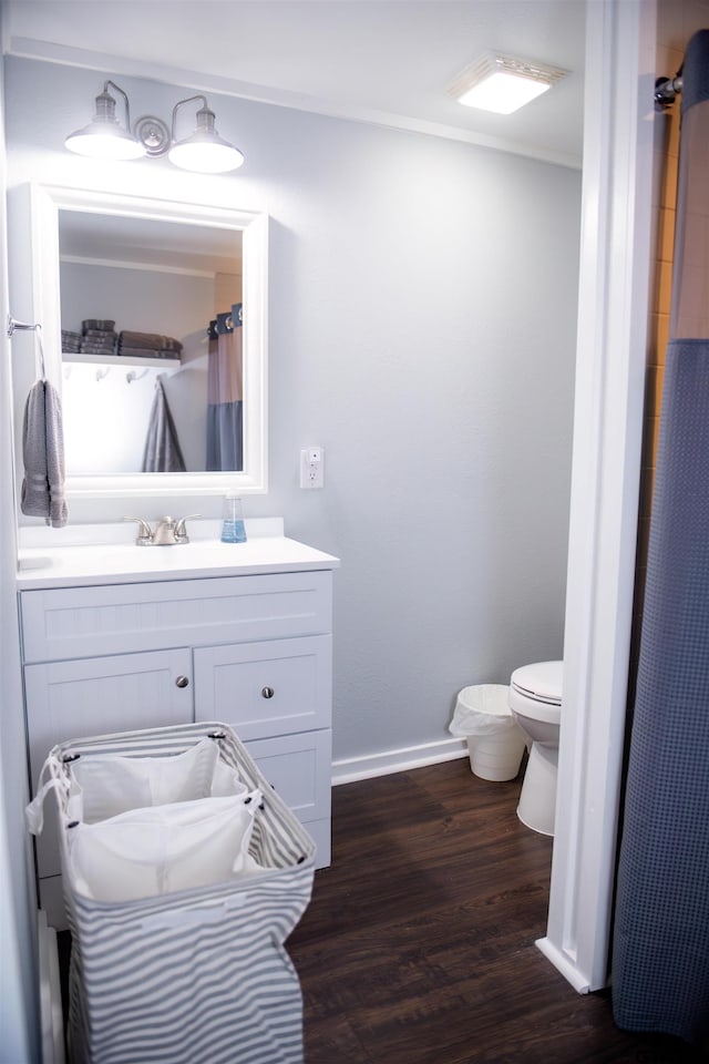 bathroom with hardwood / wood-style floors, walk in shower, vanity, and toilet