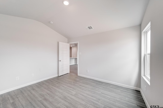 empty room with light wood-type flooring, lofted ceiling, and a healthy amount of sunlight