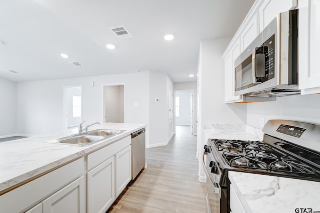 kitchen with white cabinets, sink, light hardwood / wood-style flooring, and appliances with stainless steel finishes