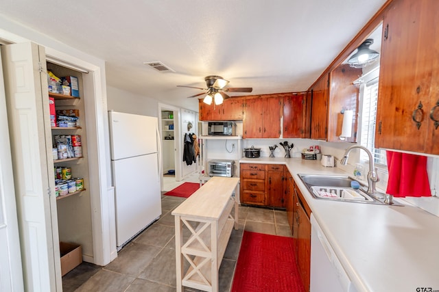 kitchen with a sink, brown cabinets, white appliances, visible vents, and ceiling fan