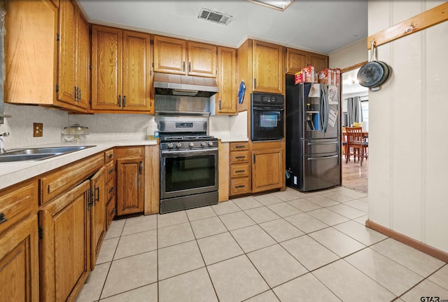 kitchen featuring black appliances, backsplash, light tile patterned floors, and sink