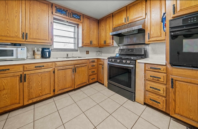 kitchen with light tile patterned floors, black oven, stainless steel gas range oven, and sink