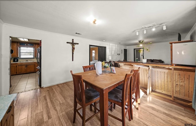 dining room featuring ornamental molding, sink, and light hardwood / wood-style flooring