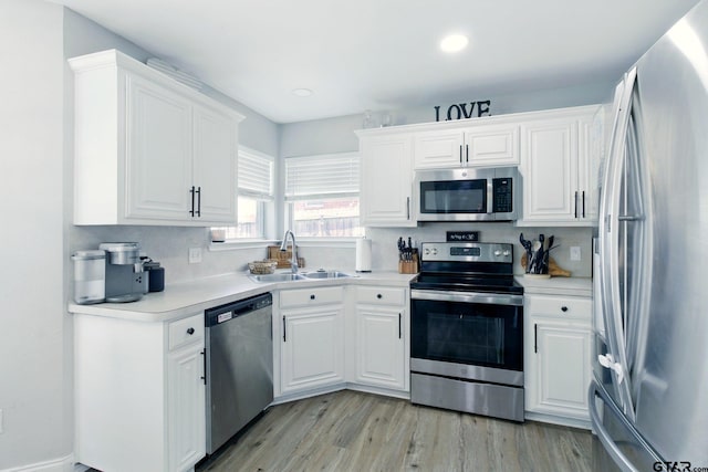 1112 E Park Dr, Lindale, TX 75771 - kitchen featuring stainless steel appliances, a sink, white cabinetry, light countertops, and light wood-style floors