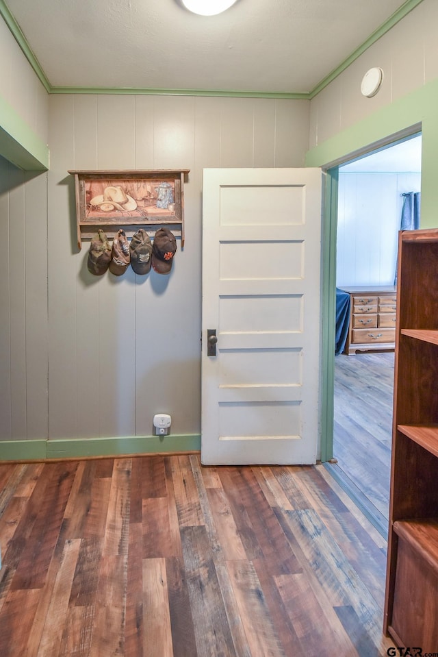 interior space featuring ornamental molding, wood finished floors, and a decorative wall