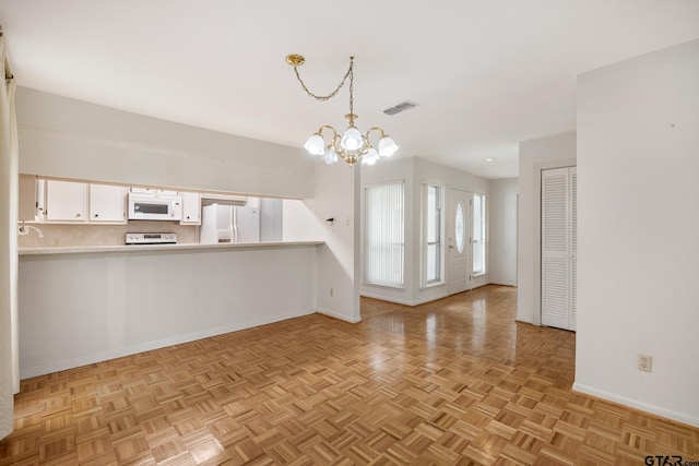 kitchen featuring white cabinetry, white appliances, a chandelier, backsplash, and visible vents