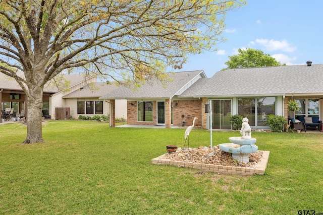 rear view of house with a lawn, a patio area, brick siding, and roof with shingles