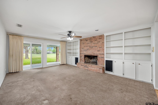unfurnished living room featuring carpet, built in shelves, ceiling fan, a brick fireplace, and visible vents