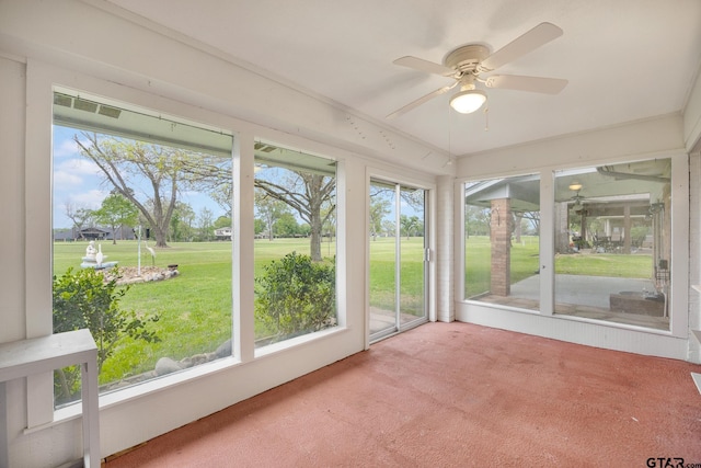 unfurnished sunroom featuring a ceiling fan and a healthy amount of sunlight