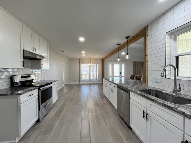 kitchen featuring stainless steel appliances, white cabinetry, backsplash, and sink