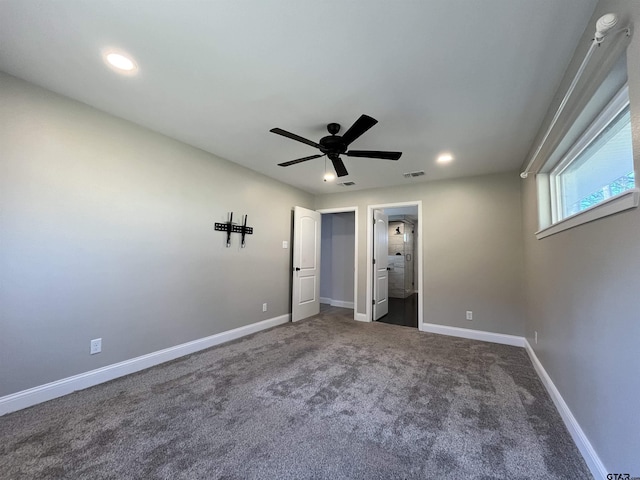 unfurnished bedroom with ceiling fan and dark colored carpet