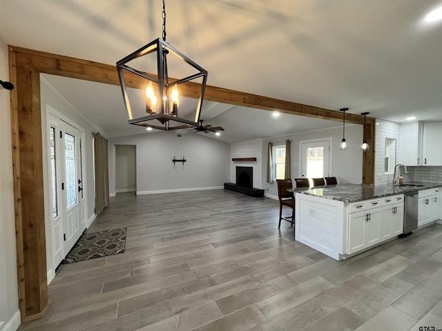 kitchen with white cabinets, dishwasher, dark stone countertops, and a fireplace