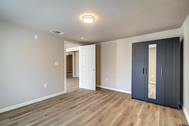 unfurnished bedroom featuring a textured ceiling and light hardwood / wood-style flooring