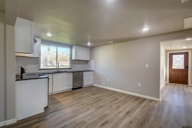 kitchen featuring backsplash, white cabinetry, dishwasher, and light wood-type flooring