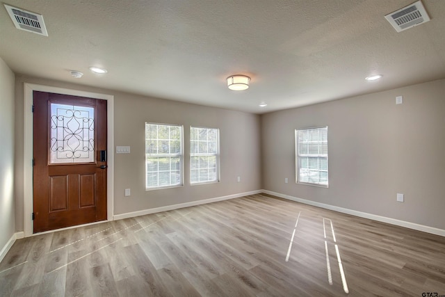 foyer entrance with light hardwood / wood-style floors and a textured ceiling