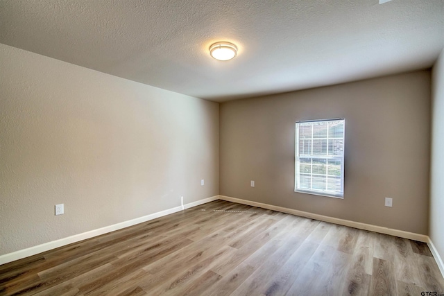 spare room featuring light hardwood / wood-style floors and a textured ceiling