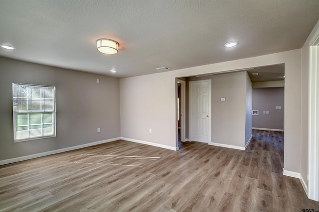 spare room with light hardwood / wood-style floors and a textured ceiling