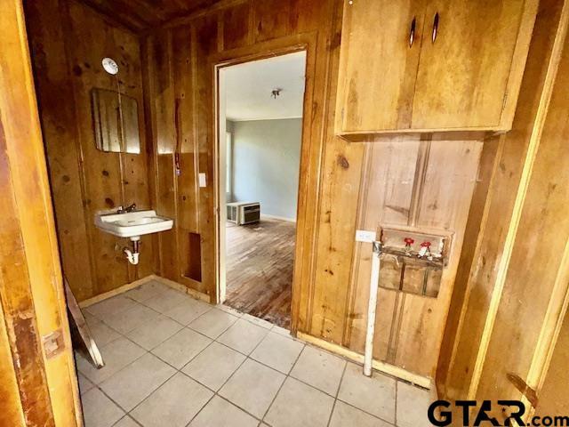 bathroom with tile patterned flooring, wood walls, and sink