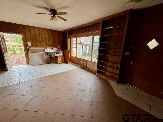 tiled foyer with ceiling fan and wooden walls