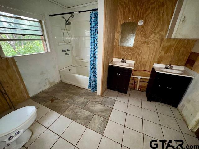 full bathroom featuring toilet, vanity, wood walls, and shower / bath combo