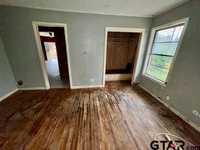 unfurnished bedroom featuring dark wood-type flooring and crown molding