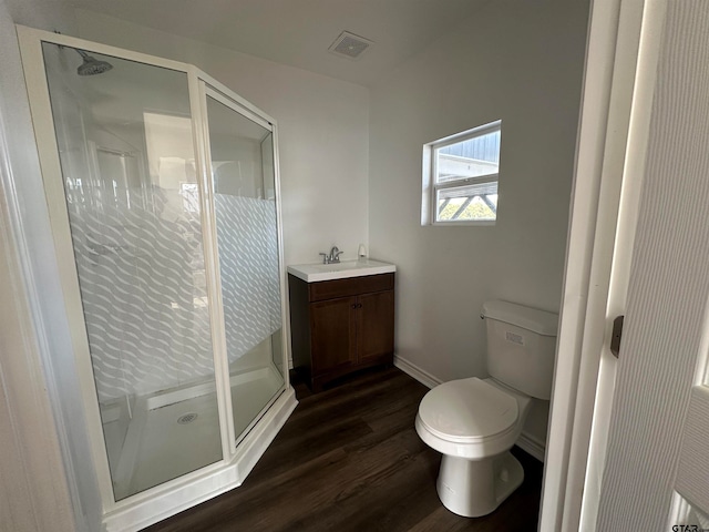 bathroom featuring toilet, vanity, hardwood / wood-style flooring, and a shower with shower door