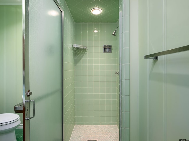 bathroom with a shower with shower door and toilet