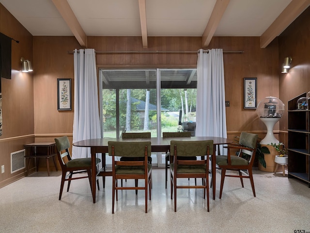 dining space with beamed ceiling and wooden walls