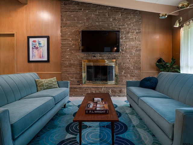 living room with a stone fireplace, wooden walls, and vaulted ceiling