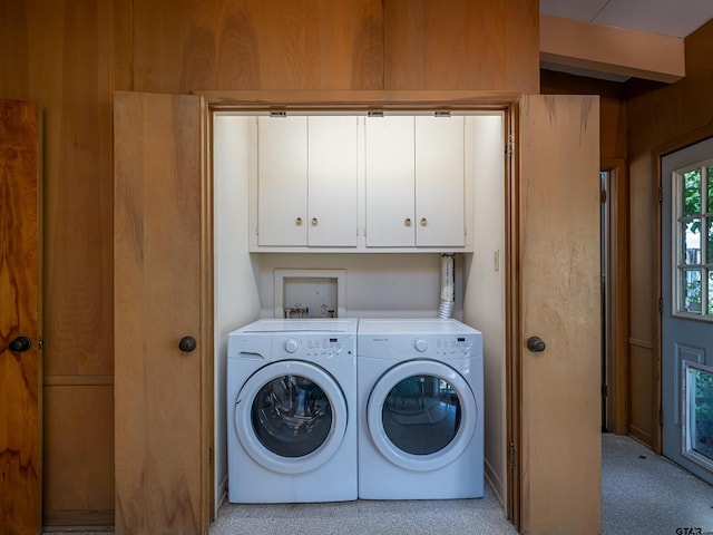 laundry room with cabinets, wooden walls, light carpet, and washer and clothes dryer