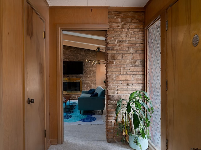 hallway featuring wooden walls, lofted ceiling, and carpet floors