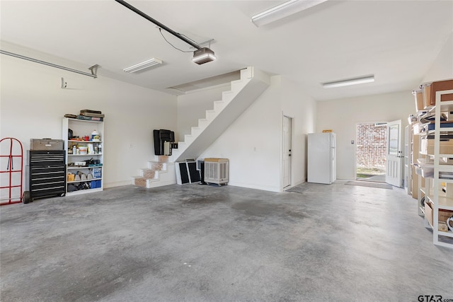 garage featuring white fridge and a garage door opener