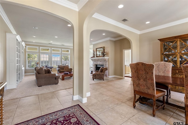 dining room featuring light colored carpet, a fireplace, and crown molding