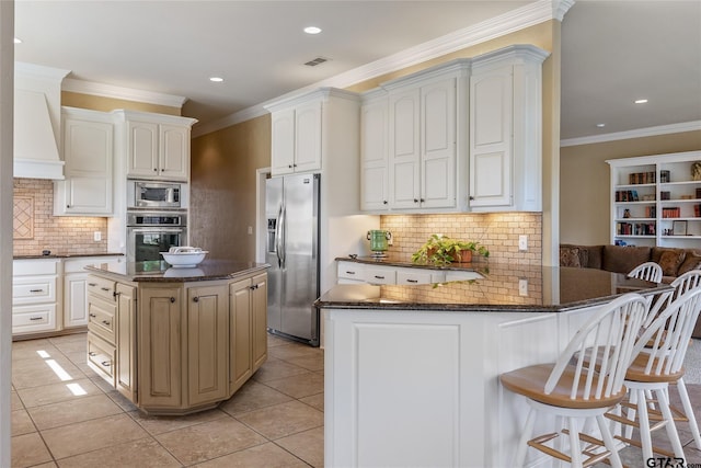 kitchen with light tile patterned floors, stainless steel appliances, white cabinetry, and kitchen peninsula