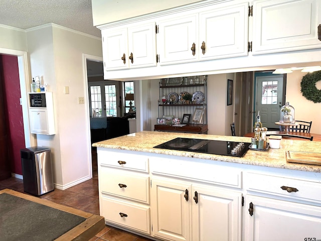 kitchen featuring white cabinetry, a textured ceiling, black electric stovetop, and dark tile patterned floors