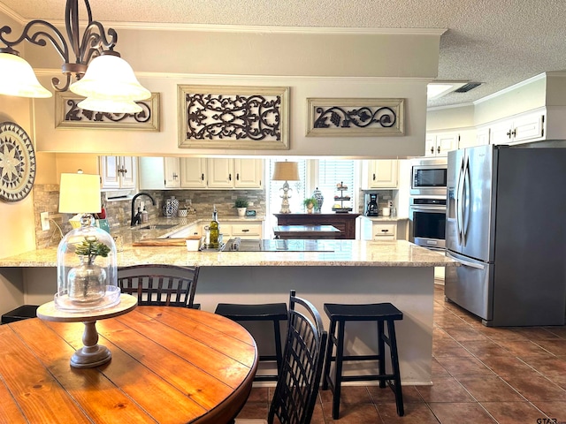 kitchen featuring kitchen peninsula, white cabinetry, pendant lighting, and appliances with stainless steel finishes