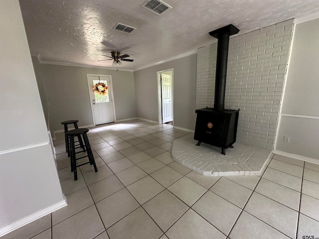 unfurnished living room with a textured ceiling, light tile patterned flooring, crown molding, and ceiling fan