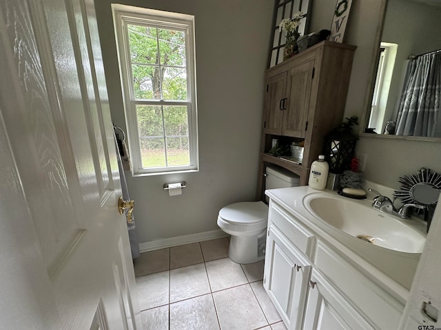 bathroom featuring toilet, vanity, a wealth of natural light, and tile patterned floors