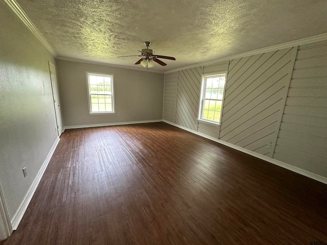 spare room with dark hardwood / wood-style flooring, wooden walls, a textured ceiling, ornamental molding, and ceiling fan