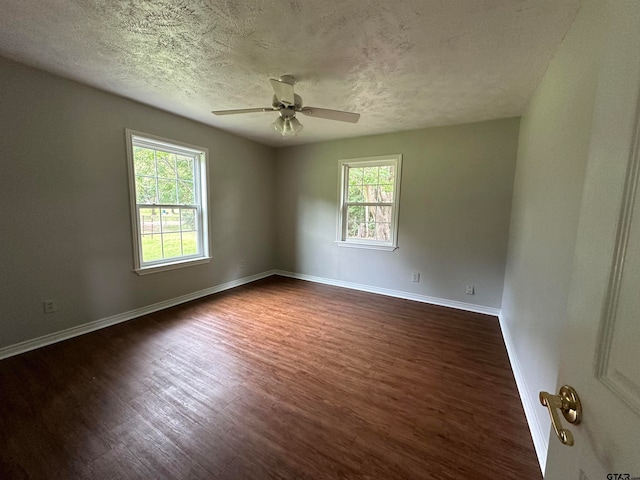 empty room featuring a textured ceiling, a healthy amount of sunlight, and dark hardwood / wood-style floors