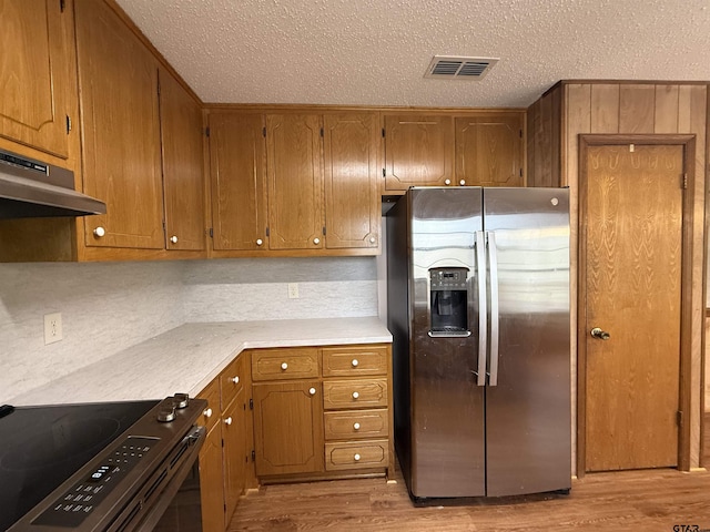 kitchen featuring tasteful backsplash, appliances with stainless steel finishes, light hardwood / wood-style floors, and a textured ceiling