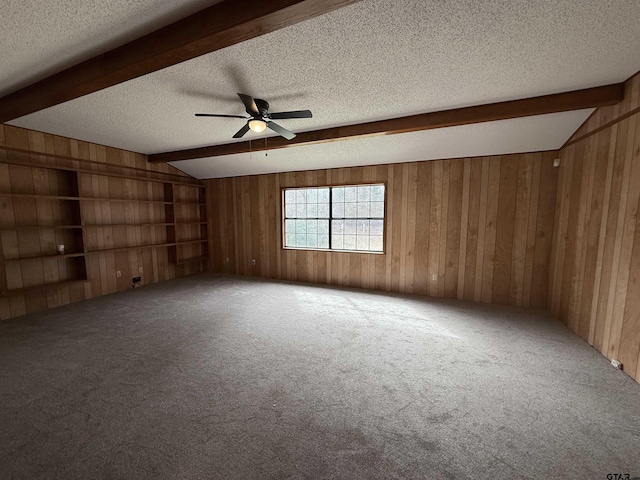 carpeted empty room with lofted ceiling with beams, a textured ceiling, and wood walls