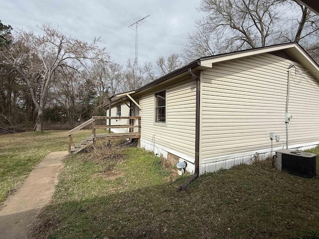 view of side of home with cooling unit and a lawn