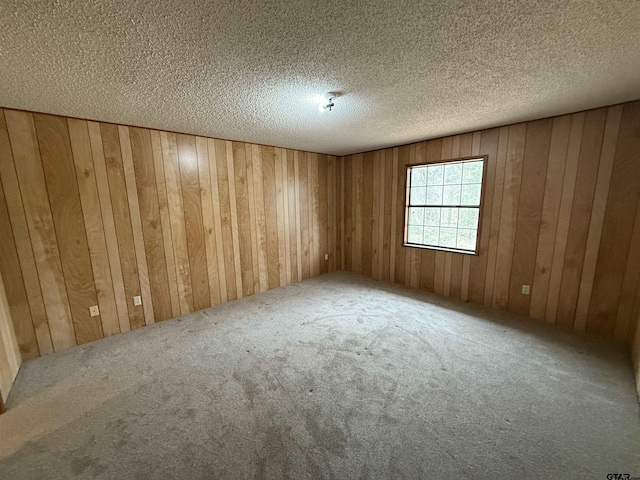 unfurnished room featuring carpet floors, wooden walls, and a textured ceiling